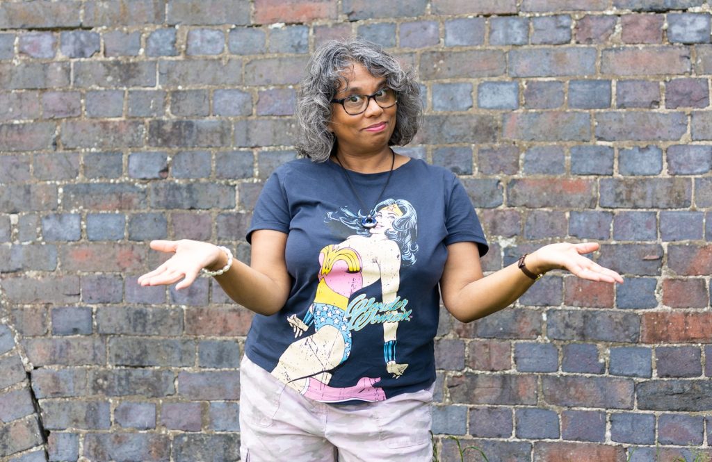 Woman in a blue T shirt with hands open and smiling